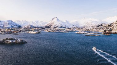 Feribot görüntüsü, soğuk İskandinav su yüzeyinden vahşi çevredeki balıkçı köyüne nefes kesici fiyortlar, İskandinav çevresi ve ufukta karlı dağlar.