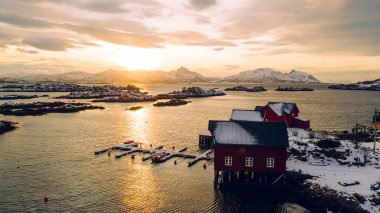 Norveç deniz suyuyla kaplı Lofoten takımadalarının nefes kesici kuş bakışı görüntüsü. Küçük balıkçı teknesinin hava görüntüsü. Altın gün batımında iskelesi olan. 