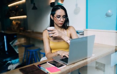 Bilgisayarda online oturum sırasında internet bilgilerini el yordamıyla araması için kahve konusunda yetenekli Kafkasyalı serbest yazar, klasik gözlüklü bir kadın kablosuz bağlantı kurmak için internetten arama yapıyor.