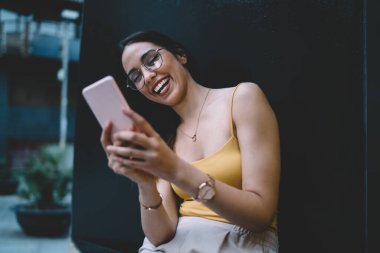 Neşeli milenyum kadın blog yazarı cep telefonu teknolojisiyle e-posta ve mesajları kontrol ediyor, gülümseyen hippi kız sosyal medya ağını taramak için 4G kablosuz akıllı telefon kullanıyor.