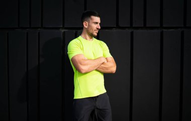 Spor giyim sektöründe kararlı erkek sporcu sabah saatlerinde şehir ortamında kardiyo eğitimi için uzaklara bakıyor ve düşünüyor. Beyaz kaslı koşucu elleri çapraz ve mükemmel vücut şekli var.