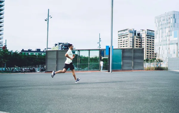 マラソンの準備をしている決定的な男性選手のサイドビューは 都市の都市で心臓の朝のトレーニングを持っています 健康的なライフスタイルを維持し 通りの周りの速度でスポーツウェアジョギングでやる気のある男 — ストック写真