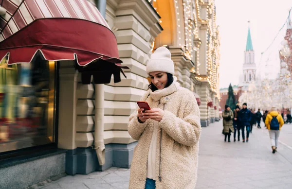 Smiling Young Female Traveler Hat Coat Scrolling Mobile Phone While — Stock Photo, Image