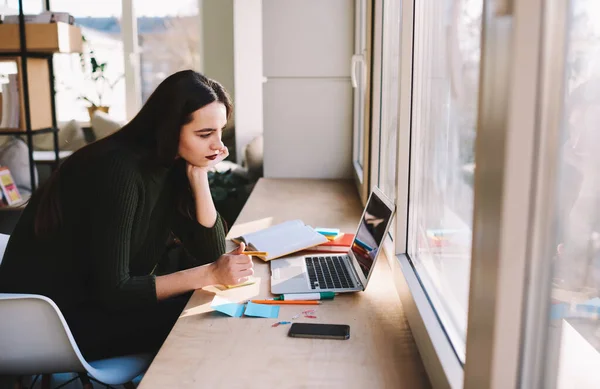 Zijaanzicht Van Serieuze Vrouwelijke Student Zittend Aan Vensterbank Met Netbook — Stockfoto