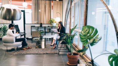 Akıllı telefon ve tablet kullanan farklı meslekdaşların yan görünüşü parlak ışıklarla aydınlatılmış çağdaş ve ferah bir ofiste otururken