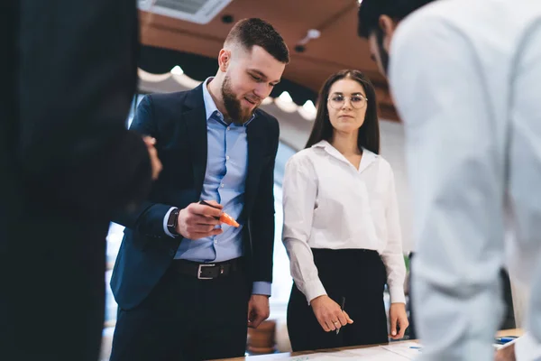 Colaboradores Enfocados Trajes Formales Parados Juntos Cerca Mesa Discutiendo Detalles — Foto de Stock