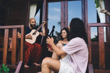 Sıcak iklimli bir ülkede tatil sırasında verandada birlikte dinlenen çok ırklı erkek ve kadın arkadaş açıları düşük.