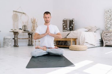 Rastgele giyinen sakin ruhlu erkek nilüfer çiçeğinde oturup pratik yaparken rahatlama ve uyum içinde poz verir. Gözleri kapalı yakışıklı beyaz adam meditasyona zaman harcar. Zihin ve bedenle ilgilenir.