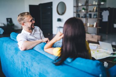 Keyifli iş arkadaşlarının rahat koltukta oturup birbirleriyle oturma odasındaki iş hakkında konuşmalarının arkası.