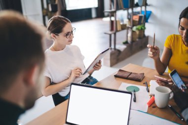 Modern aletlerle çeşitli öğrenciler ortak projenin detaylarını tartışırken masadaki rahat ortak odada dizüstü bilgisayarla oturuyorlar.