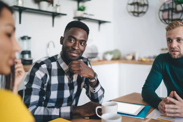 Geconcentreerde Jonge Diverse Mannelijke Medewerkers Zitten Aan Tafel Luisteren Aandachtig — Stockfoto