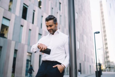 Beyaz gömlekli beyaz iş adamı finans merkezindeki şirket ortağını bekliyor. Takılabilir kol saati için görüşme saatini kontrol ediyor. Kendine güvenen, gururlu, cep telefonlu bir CEO 'su var.