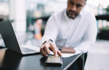 Bulanık iş adamı, mesajlaşmak için akıllı telefon klavyesi kullanıyor ve sokak kafesindeki mesai sırasında mesajlar gönderiyor, 4G ile bağlantılı modern akıllı telefon teknolojisine odaklanıyor