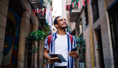 Modern aletleri olan Afro-Amerikan bir hippi tarihi merkezde geziyor tatil tatillerinde şehri keşfediyor, koyu tenli bir erkek milenyuma gülümsüyor ve cep telefonuyla geziniyor.