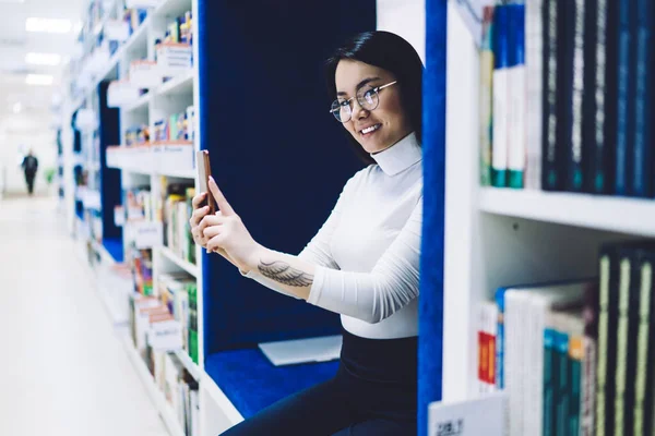 Zijaanzicht Van Vrolijke Glimlachende Aziatische Vrouwelijke Student Bril Zittend Bibliotheek — Stockfoto