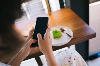 Süslü giysiler içinde isimsiz bir kadının yemekhanedeki leziz kremalı pastayla cep telefonunda sohbet etmesinden.