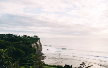 Güneşli bir günde, doğada bulutlu gökyüzüne karşı yuvarlanan köpüklü deniz dalgalarından.
