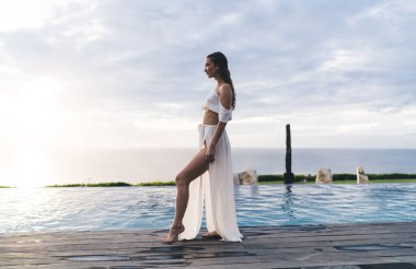 Uzun, ince, çıplak ayaklı, zarif elbiseli bir kadın. Sakin gölün yanındaki ahşap yolda dikiliyor ve gözlerini kaçırıyor.