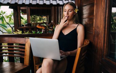 Şaşırmış kadın işçiler sorunlarını dizüstü bilgisayarla hallediyorlar ve yaz tatilini sıcak bir ülkede geçirirken açık kafede oturuyorlar.