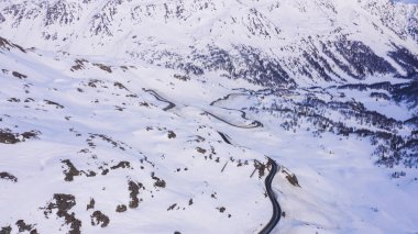 Karlı araziden dağlara doğru giden dar ve kıvrımlı bir yoldan doğada kış günü kışın kırağı kaplayan yamaçlara doğru.