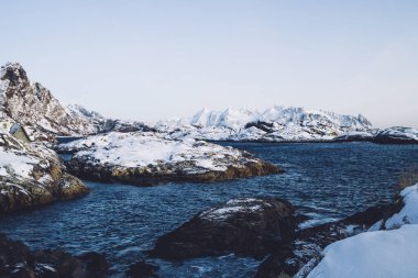 Soğuk, koyu mavi nehir, Norveç 'te açık gökyüzünün altında kayalık kayalıklarla kaplı yaban fiyortlarda akıyor.
