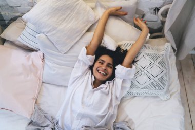 Pozitif pazar sabahı uyanırken uykusunda esneyen neşeli kadın, neşeli beyaz kadın hafta sonları tembel bir şekilde uyanıyor ve rahat yatak odasında dinleniyor.