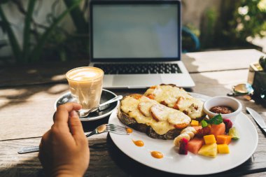 Lezzetli tostlar ve kafenin terasında modern netbook 'un yanında bir bardak cappuccino ile masada oturan yüzü olmayan kişi.