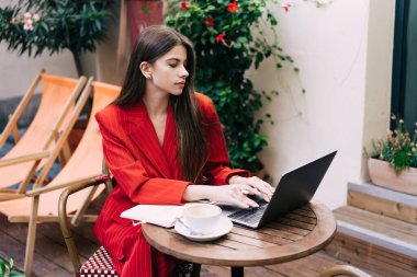 Gündüz vakti sokak kafesinde kahve içerken dizüstü bilgisayarında daktilo yazan zarif kadın serbest yazar.