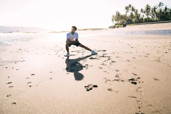 太陽の下で熱帯雨林やライマンの近くのビーチでトレーニングをしながら 快適な着用でスポーティ若い男 — ストック写真