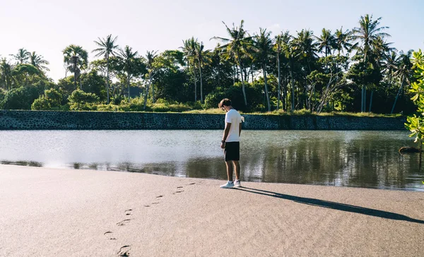 해변을 걸어가면서 근처에 연못을 바라보고 청년의 — 스톡 사진