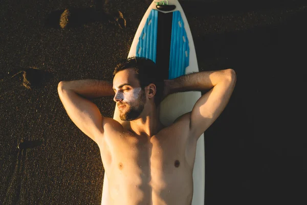 在巴哈马岛上 20岁的白人男子在晚上放松下来 躺在加利福尼亚迈阿密海滩自己的冲浪板上享受黄昏和日落的轻松自在的年轻男性冲浪旅行者 — 图库照片