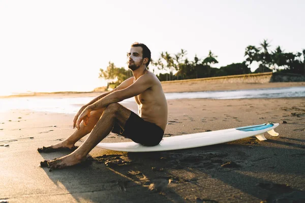 Młody Surfer Bez Koszulki Grubą Warstwą Blokera Słońca Twarzy Siedzący — Zdjęcie stockowe