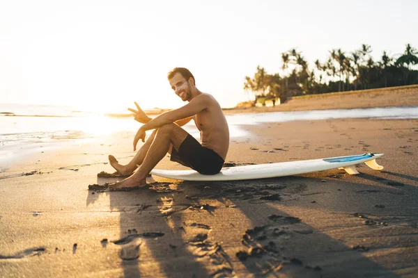 Πλευρική Άποψη Της Shirtless Αρσενικό Surfer Κοιτάζοντας Κάμερα Και Δείχνει — Φωτογραφία Αρχείου
