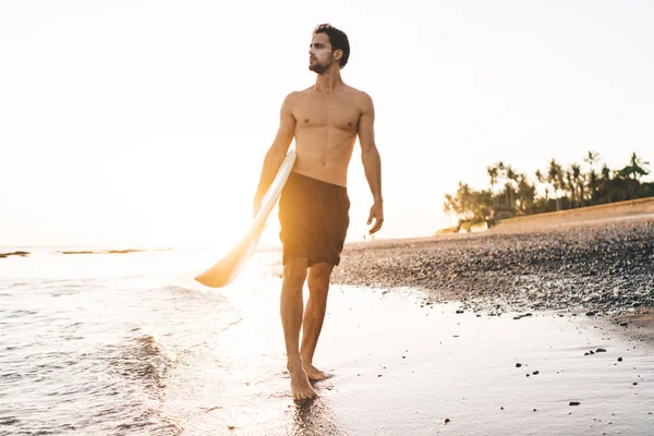 Kolunun Altında Sörf Tahtası Olan Genç Bir Sporcu Sahilde Yürüyor — Stok fotoğraf