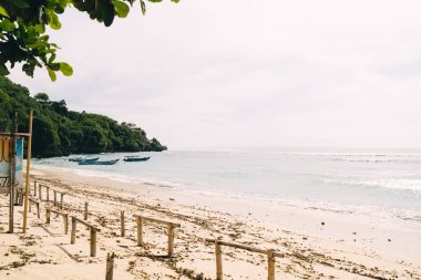Boş kumsal manzarası ve dalgalı deniz gri bulutlu gökyüzü ve yaz gününde yeşil pelerin