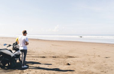 Kimliği belirsiz erkek hipsterın deniz kenarında insansız hava aracı fırlatıp tropikal tatil beldesinde vakit geçirirken plajda takıldığı arka plan görüntüsü.