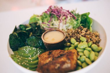 Daha yakından bakınca, az yağlı ve vitamin ve vitaminle dengelenmiş lezzetli, az yağlı organik yemek resminin yukarısından soslu ve taze sebzeli, otlu ve baharatlı lezzetli yiyeceklerin görüntüsü.