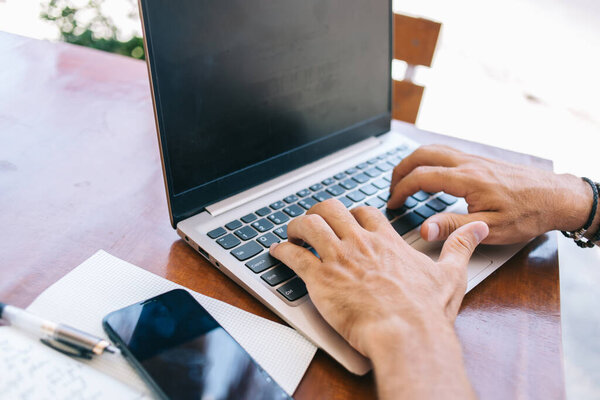 Cropped image of caucasian male typing on laptop computer on remote job browsing web page for share multimedia content, man's hand on keyboard publication text in blog via wireless internet connection
