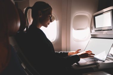 Modern dizüstü bilgisayarda uzak mesafe işi yapmak için internete bağlanan yetenekli kadın yolcu, internet üzerinden internet üzerinden mesaj atan beyaz kadın, birinci sınıfta oturuyor.