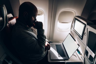 Yukarıdan bakıldığında sıradan giyinen erkek girişimci yolcu koltuğunda oturuyor ve uçuş sırasında netbook 'tan okuyor.