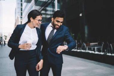 Katı siyah takım elbiseli mutlu çok ırklı iş arkadaşları yazın şehir merkezinde sokakta izlenen her bilek saatinde konuşuyorlar.