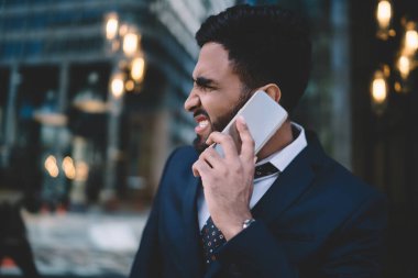 Mavi takım elbiseli, asık suratlı yakışıklı erkek yönetici cep telefonunda sorun yaşıyor ve şehir merkezinde geçmişi bulanık. 