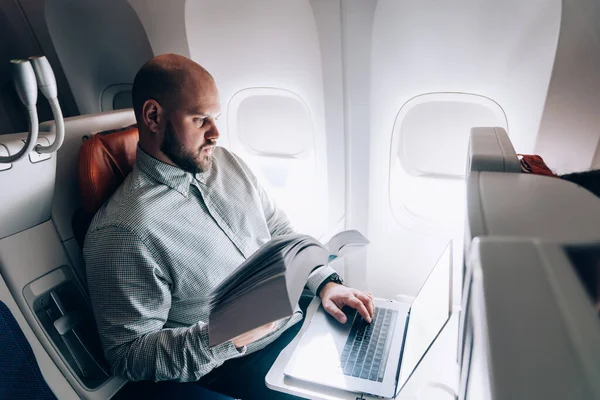 Yazar ve gazeteci ile uçuş sırasında iş toplantısından önce uçakta metin oluşturmak için edebiyat ve dizüstü bilgisayar uygulamaları tutan akıllı erkek kitap editörü
