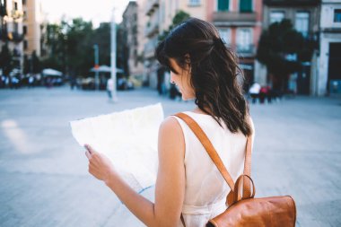 Sırt çantalı, gülümseyen ve boş kağıt haritayı inceleyen turist şehrinin sokaklarında duran neşeli gezginin arka planı