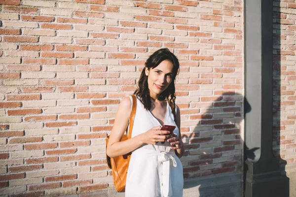 Молодая Туристка Белом Комбинезоне Улыбается Глядя Смс Камеры Используя Смартфон — стоковое фото