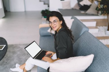 Görme düzeltmesi için gözlüklü zengin beyaz kadın portresi evdeki uzak iş için kablosuz bağlantının keyfini çıkarıyor, milenyum tebessümlü hippi kız dizüstü bilgisayar kullanarak ekranı taklit ediyor.