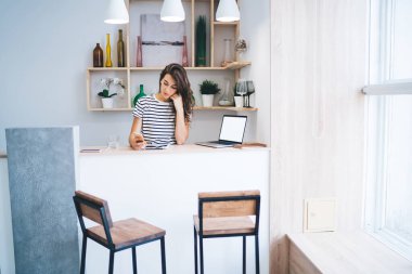 Düşünceli Kafkas kadın serbest çalışan cep telefonu bildirimini kontrol eden ev içi çalışan, ciddi milenyum yeniyetme kız laptopun yanına mesaj yolluyor.