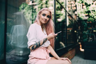 Yeni nesil Z 'nin modern cep telefonu cihazıyla şehir merkezinde dinlendiği yumuşak odaklı görüntü, akıllı telefonlu düşünceli beyaz blog yazarı içerik fikri yaratıyor.