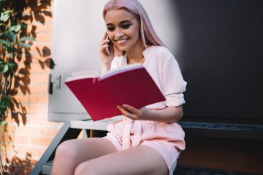 Cep telefonu danışmanlık görüşmesi sırasında gülümseyen mutlu beyaz öğrenci üniversite eğitimi hakkında konuşuyor, neşeli pembe saçlı kadın cep telefonu uygulaması üzerinden not defteri bilgilerini analiz ediyor.