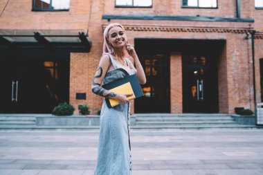 Hücre uygulaması aracılığıyla uluslararası iletişim kurarken elleri dövmeli, neşeli tasarımcının yarısı kameraya gülümsüyor. Eğitimli, kitap okuyan mutlu bir bayan öğrenci aradığı için 4 G 'de geziniyor.